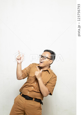 Profile of Indonesian school teacher wearing khaki uniform. Excited Indonesian government worker pointing left into empty space. Profile of Indonesian school teacher wearing khaki uniform. Excited Indonesian government worker pointing left into empty space. 123756793