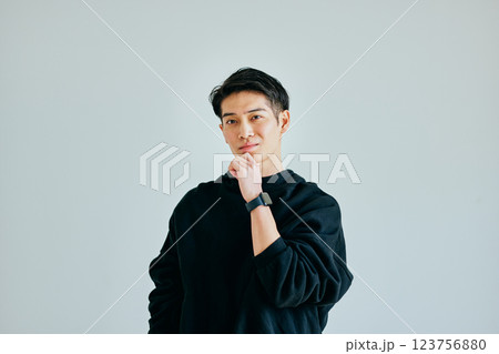 あごに手を当てて考える20代の若い男性 123756880
