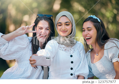 Selfie, phone and friends in nature park relax, bond or enjoy outdoor quality time together on spring day. Smile, goofy or fun group of people, girl or diversity women post to online social media app 123757977