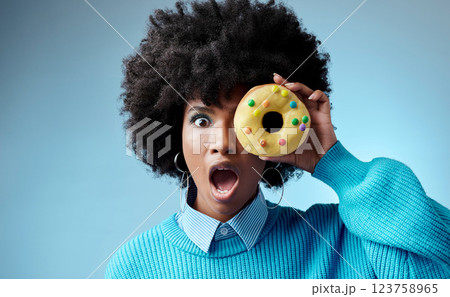 Wow, surprise and donut on eye of black woman feeling shocked with sugar, dessert or sweets against a blue background studio. Candy, food and cake with girl and omg emotion for deal, sale or alert Wow, surprise and donut on eye of black woman feeling shocked with sugar, dessert or sweets against a blue background studio. Candy, food and cake with girl and omg emotion for deal, sale or alert 123758965