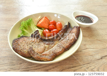 grilled black pepper pork chop steak and lettuce with tomato couple boiled carrot on plate dipping barbecue sauce in cup 123759032