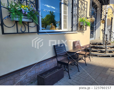 A beautiful facade with a window, planters with flowers and brown benches. 123760157