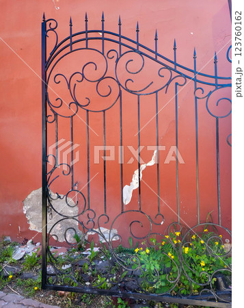 Beautiful wrought-iron wrought-iron gate leaf on the background of a red wall 123760162