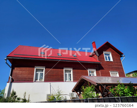 A brown house with a red roof against a blue sky background. A brown house with a red roof against a blue sky background. 123760164