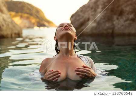 Nude sexy woman in water at sunset. Beautiful blonde woman with short wet hair and big breasts, art portrait in sea 123760548