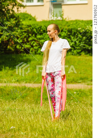 Girl doing exercises outdoor, using resistance fit band. 123760912