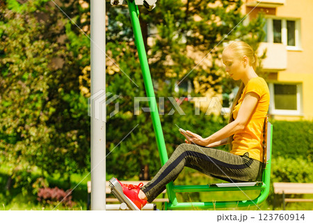 Girl doing exercises outdoor, holding phone 123760914