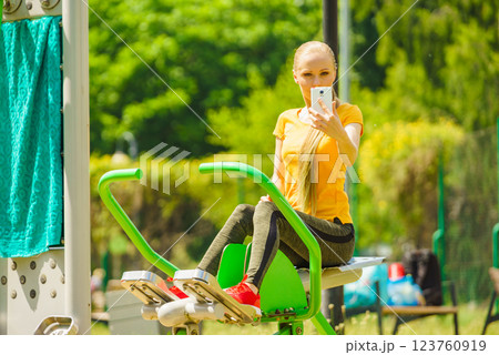 Girl doing exercises outdoor, holding phone 123760919