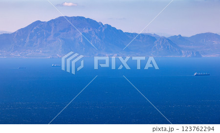 View from Gibraltar, British Overseas Territory on the Iberian Peninsula. Distant mountain range viewed across a calm expanse of ocean, with a few ships visible on the horizon. View from Gibraltar, British Overseas Territory on the Iberian Peninsula. Distant mountain range viewed across a calm expanse of ocean, with a few ships visible on the horizon. 123762294