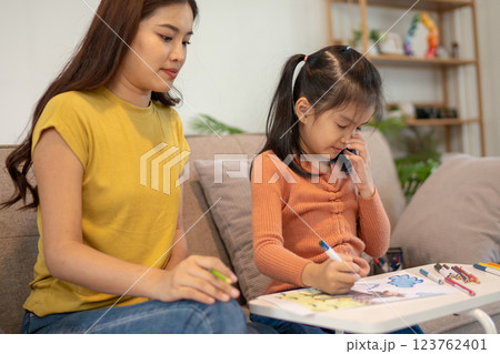 Lovely mom and little young daughter spending time together in their living room. Lovely mom and little young daughter spending time together in their living room. 123762401