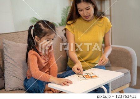 Lovely mom and little young daughter spending time together in their living room. Lovely mom and little young daughter spending time together in their living room. 123762413