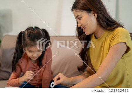 Lovely mom and little young daughter spending time together in their living room. Lovely mom and little young daughter spending time together in their living room. 123762431