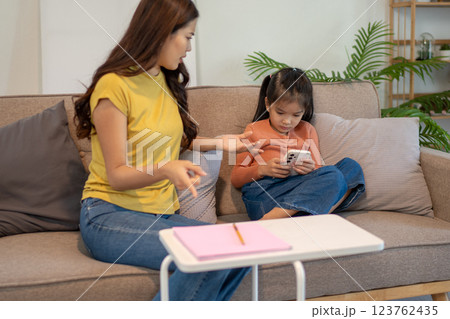 Lovely mom and little young daughter spending time together in their living room. Lovely mom and little young daughter spending time together in their living room. 123762435