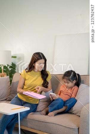 Lovely mom and little young daughter spending time together in their living room. Lovely mom and little young daughter spending time together in their living room. 123762437