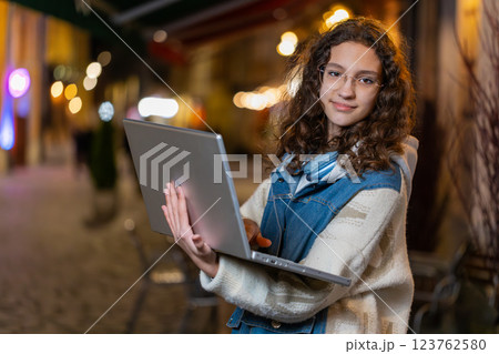 Portrait of girl working online distant job with laptop in city street browsing website chatting Portrait of girl working online distant job with laptop in city street browsing website chatting 123762580