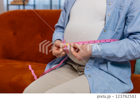 Pregnant woman measuring belly diameter with measure tape awaiting childbirth monitoring body change Pregnant woman measuring belly diameter with measure tape awaiting childbirth monitoring body change 123762581