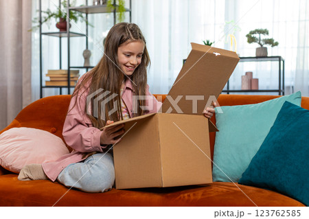 Happy amazed child kid girl unpacking delivery parcel opening cardboard box receiving purchase gift Happy amazed child kid girl unpacking delivery parcel opening cardboard box receiving purchase gift 123762585