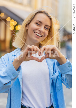 Woman makes symbol of love showing heart sign to camera charity gratitude donation positive feelings 123762614