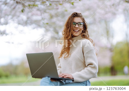 Happy female freelancer sitting in the office with a laptop. Nature and urban lifestyle concept. 123763004