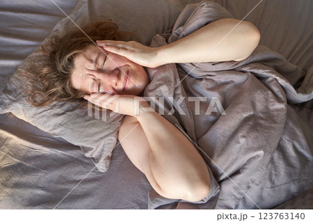 Caucasian adult female lying in bed with headache holding her head in painful 123763140