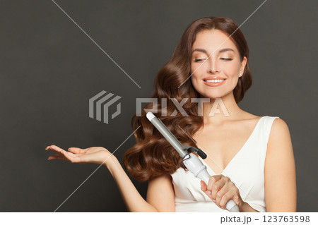 Young woman with healthy long wavy hair  holding empty palm hand  123763598