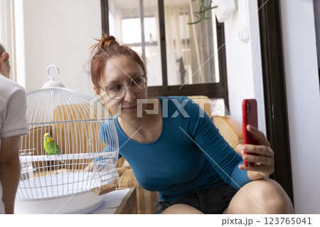 Woman taking photos of parrot in cage with smartphone 123765041