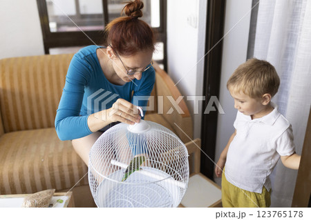 Mother and son caring for pet parrot in living room Mother and son caring for pet parrot in living room 123765178