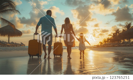Family walking along the beach at sunset with luggage in tow Family walking along the beach at sunset with luggage in tow 123765251