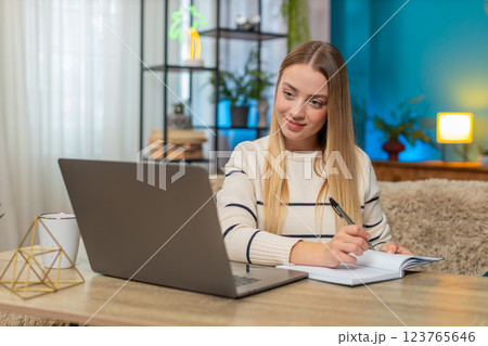 Caucasian woman smiling, finding inspiration at home on table, typing on laptop, remote education Caucasian woman smiling, finding inspiration at home on table, typing on laptop, remote education 123765646
