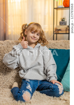 Young teenager girl showing thumbs up with a happy expression and positive attitude indoors at home Young teenager girl showing thumbs up with a happy expression and positive attitude indoors at home 123765668