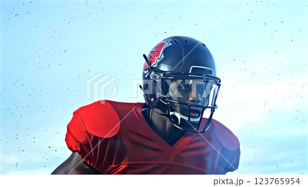 Afro-American football player in red helmet and uniform, intense expression framed by protective facemask, powerful posture emphasizing strength, focus, and resilience under bright blue sky. 123765954