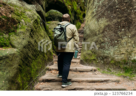 A tourist with a backpack stands against the background of a mountains. Young 30s blonde man hiking in nature. Travel, adventure. Concept of an active lifestyle. High quality photo. A tourist with a backpack stands against the background of a mountains. Young 30s blonde man hiking in nature. Travel, adventure. Concept of an active lifestyle. High quality photo. 123766234