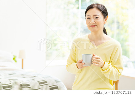 ベッドでコーヒーを飲むミドル女性 123767112