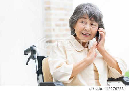 スマホで電話をする車椅子のシニア女性 スマホで電話をする車椅子のシニア女性 123767284