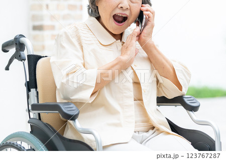 スマホで電話をする車椅子のシニア女性 123767287