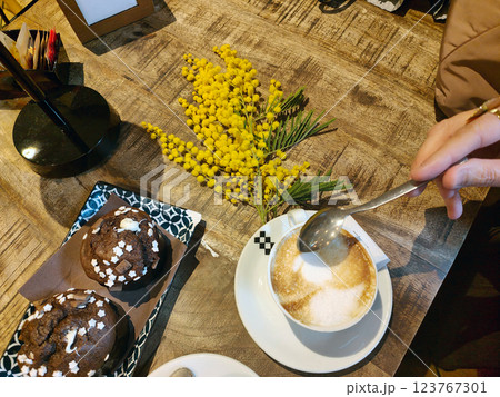 Twig of mimosa flowers on a table with coffee and muffins. Women day. Twig of mimosa flowers on a table with coffee and muffins. Women day. 123767301