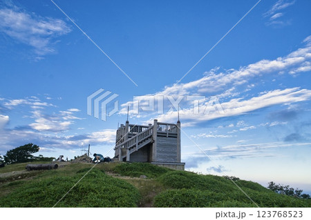 青空と広がる雲に囲まれた山頂の展望台 123768523