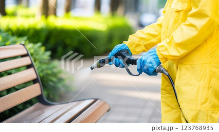 Close up of workers using a pressure washer to clean park benches 123768935