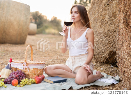 Portrait of woman in top and shorts with glass of red wine on picnic Portrait of woman in top and shorts with glass of red wine on picnic 123770148