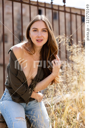 Woman in unbuttoned blouse posing near fence 123770149