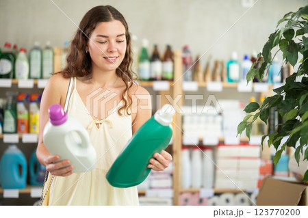Young woman buyer chooses detergent in store Young woman buyer chooses detergent in store 123770200