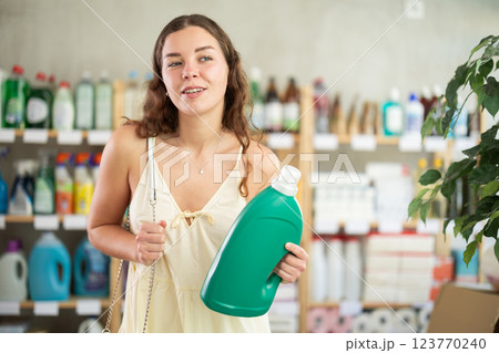 Young woman buyer chooses detergent in store 123770240