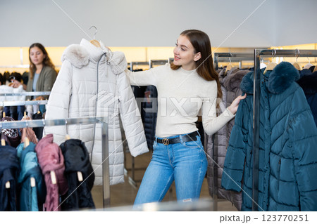 Young woman choosing insulated coat in store Young woman choosing insulated coat in store 123770251