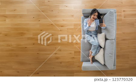 High angle view of happy cheerful positive young Asian woman on the phone at hom 123770320