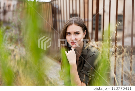 Woman posing near fence against abandoned building 123770411
