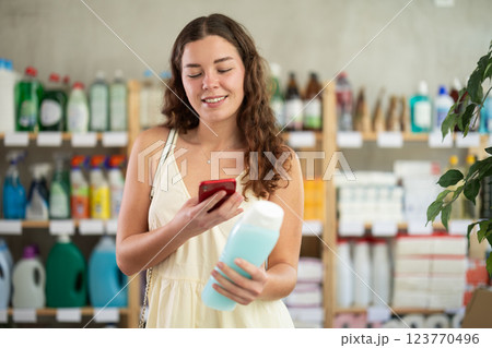 Checking expiration date of shampoo or shower gel - female shopper scans QR code on label of shampoo using smartphone 123770496