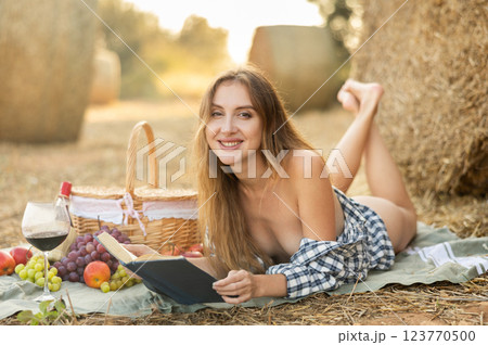 Sexy girl in plaid shirt reading book at picnic near hay bale 123770500