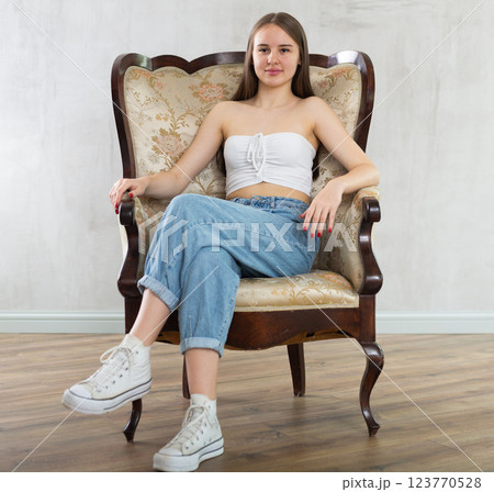 Portrait of charming girl sitting on armchair at home. woman on armchair 123770528