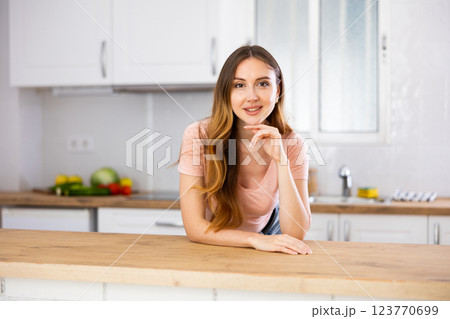 Portrait of young woman leaning on kitchen table 123770699