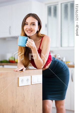 Young woman standing at kitchen with cup Young woman standing at kitchen with cup 123770721